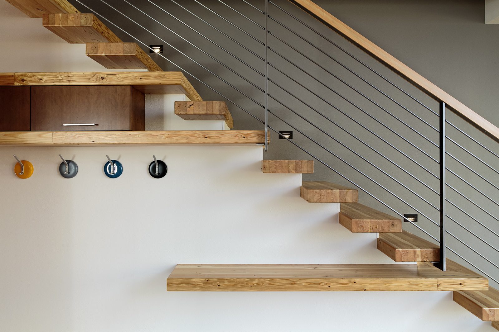 Custom floating wood stairs with cable railing in a finished interior